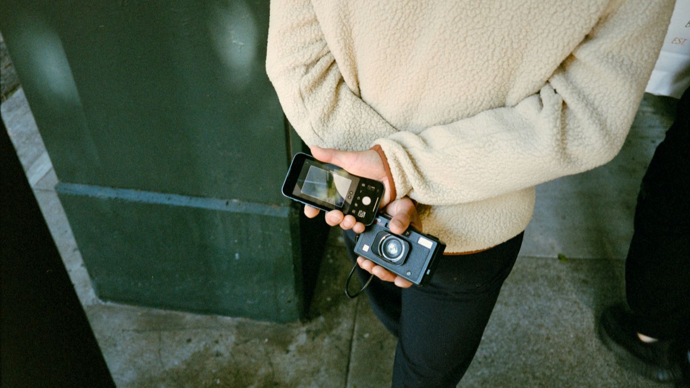 Person holding a smartphone and a digital camera