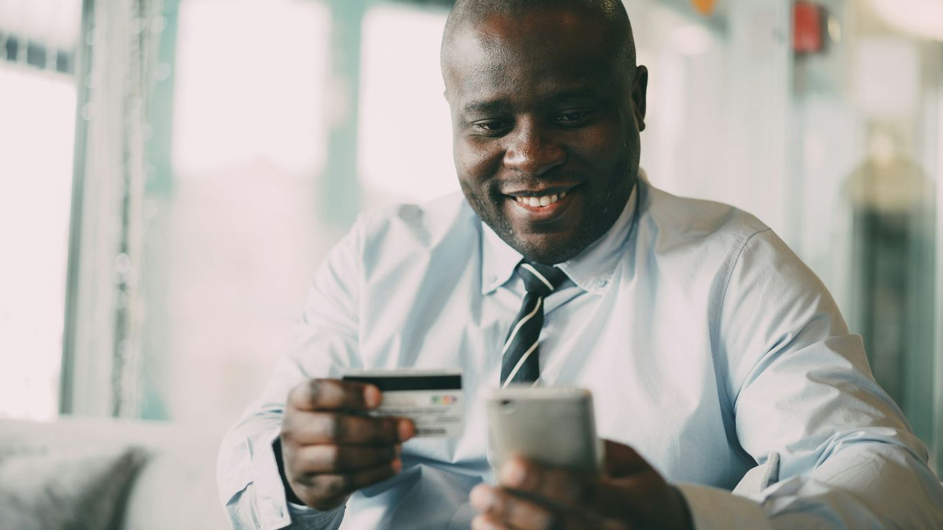 Man smiling while holding credit card and phone