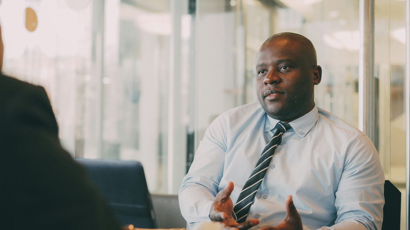 Man in a light blue shirt and tie talking.