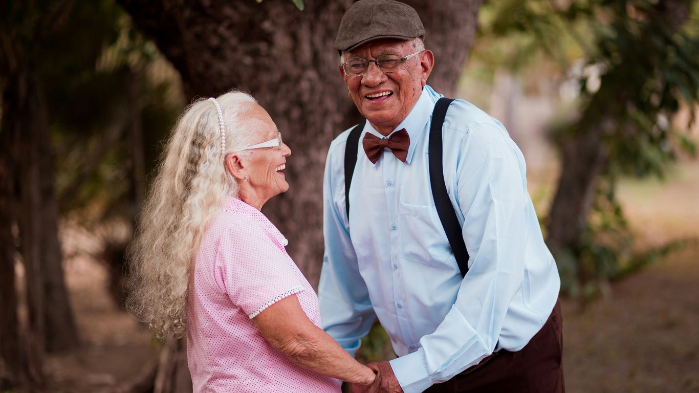 A man and woman standing next to each other near a tree