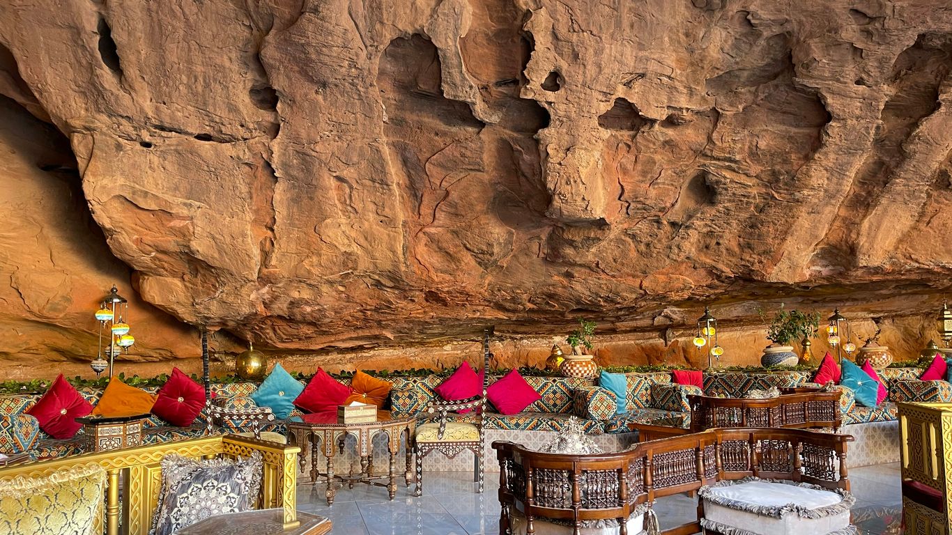 a restaurant with tables and chairs in front of a cliff
