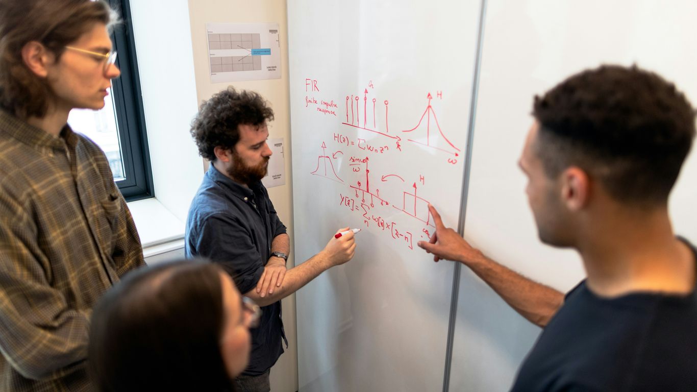 man in black crew neck t-shirt writing on white board