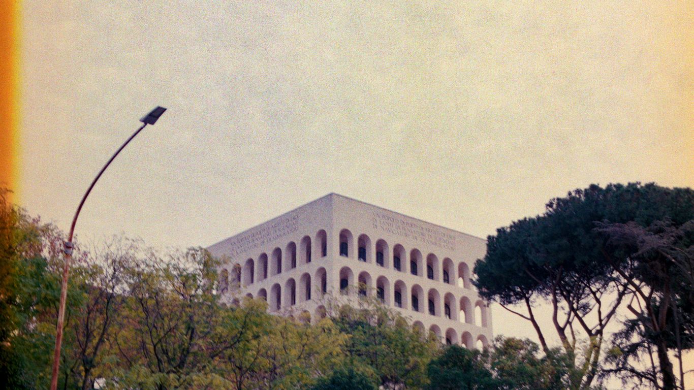 Modern building with arched windows surrounded by trees.