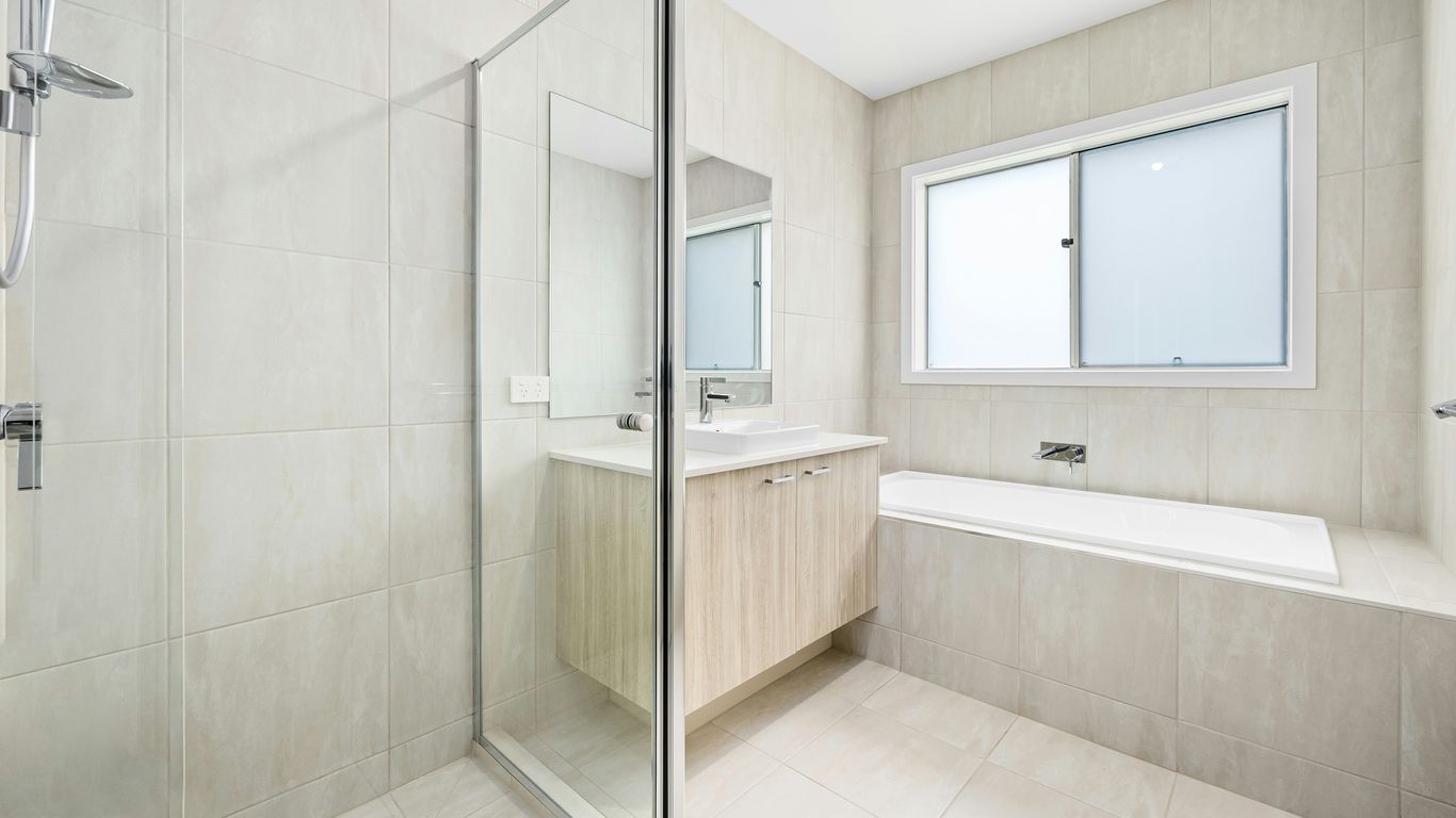 A white bathroom with a glass shower door