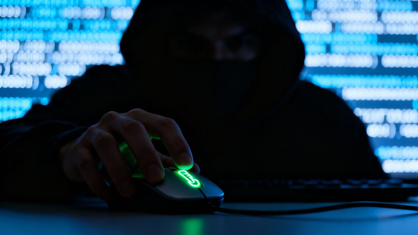 Hacker manipulating a computer mouse to click a link.