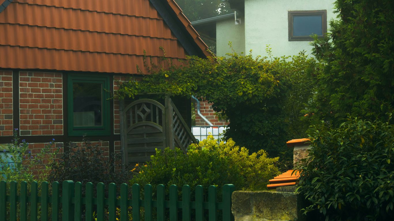 A house with a red roof and a green fence