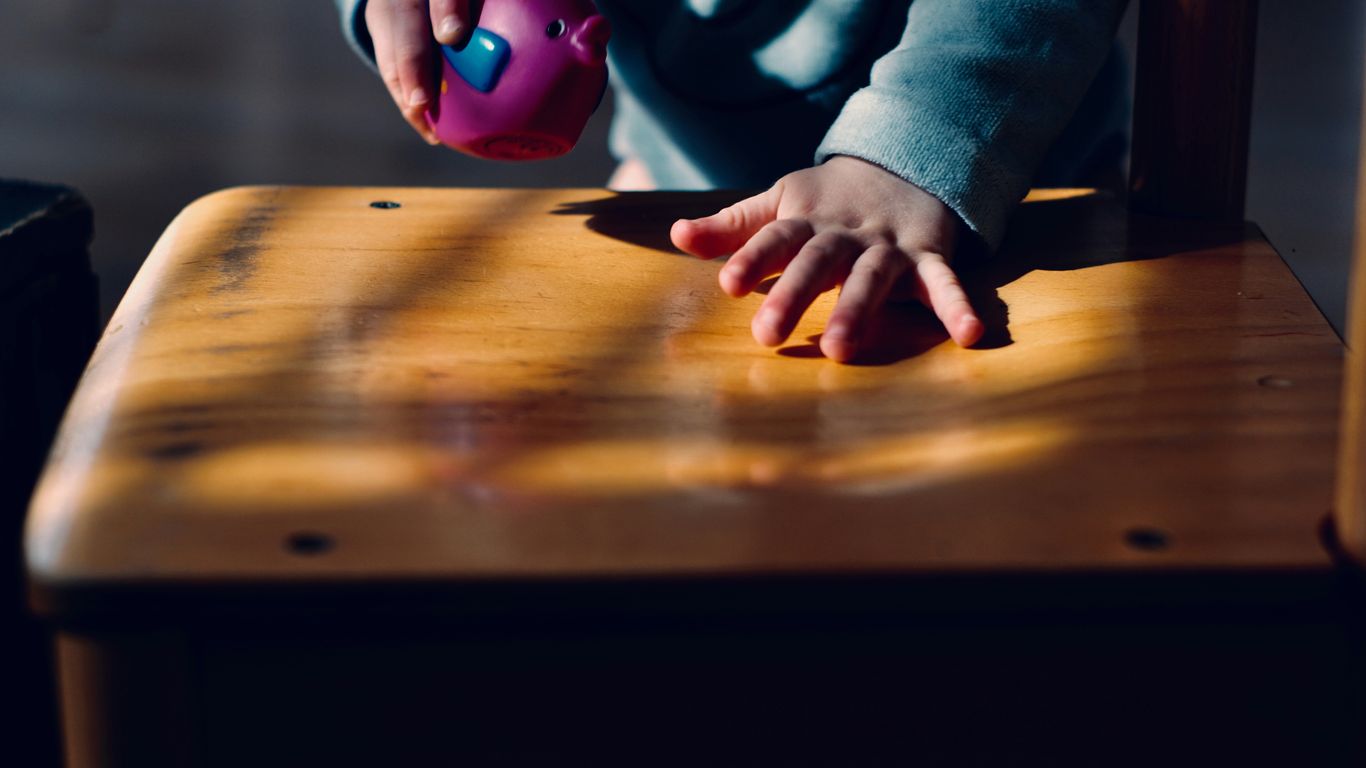 toddler playing on table while holding purple ball
