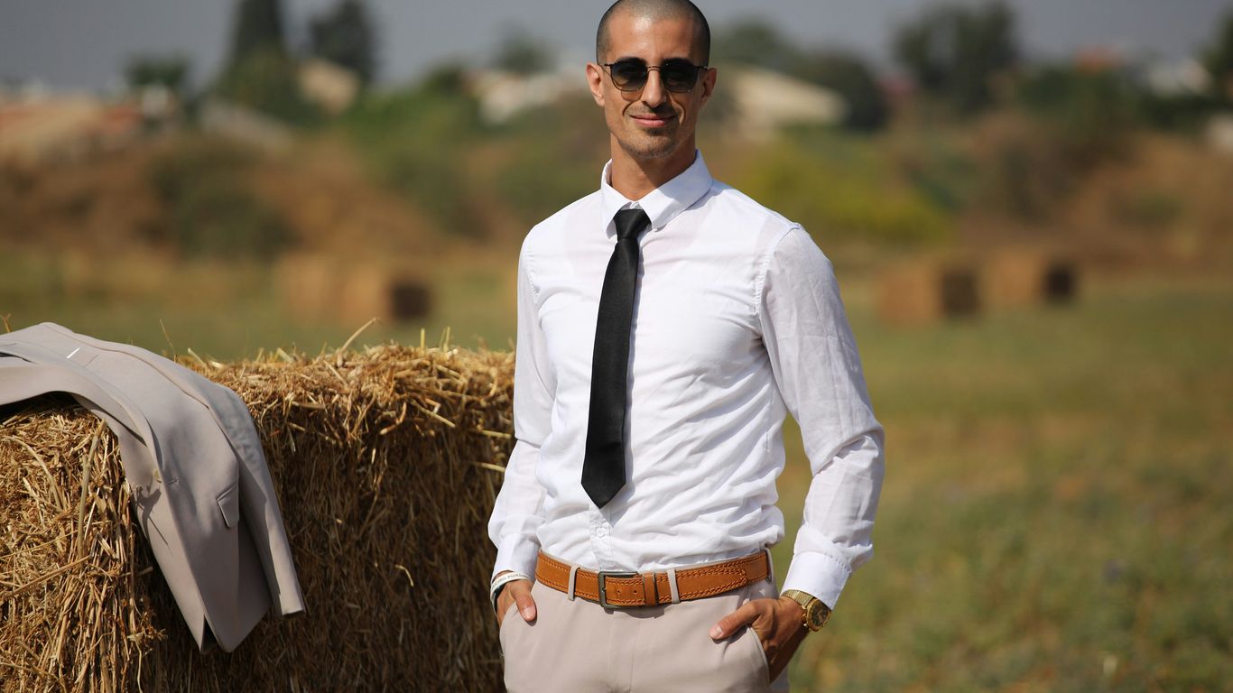 man in white dress shirt and black necktie standing on brown grass field during daytime