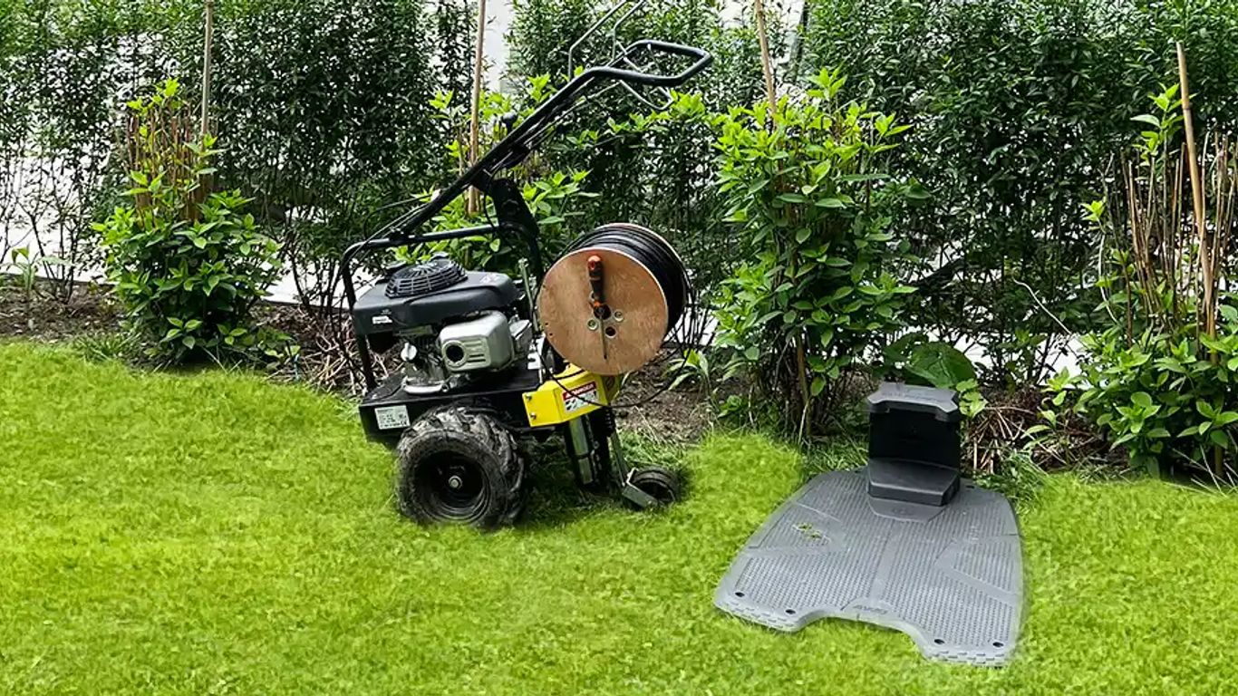 A grass-covered area with a garden tool and mat.