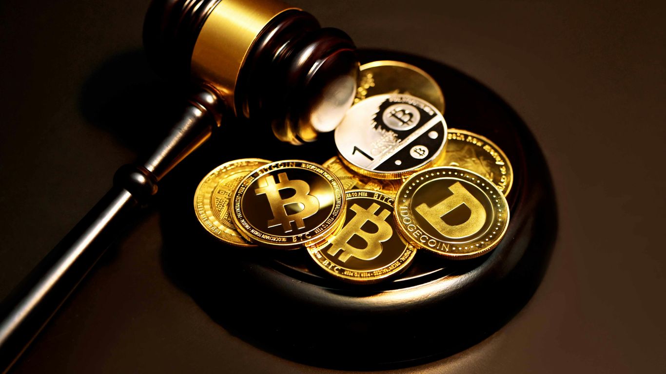 A gavel rests atop various cryptocurrency coins on a surface.