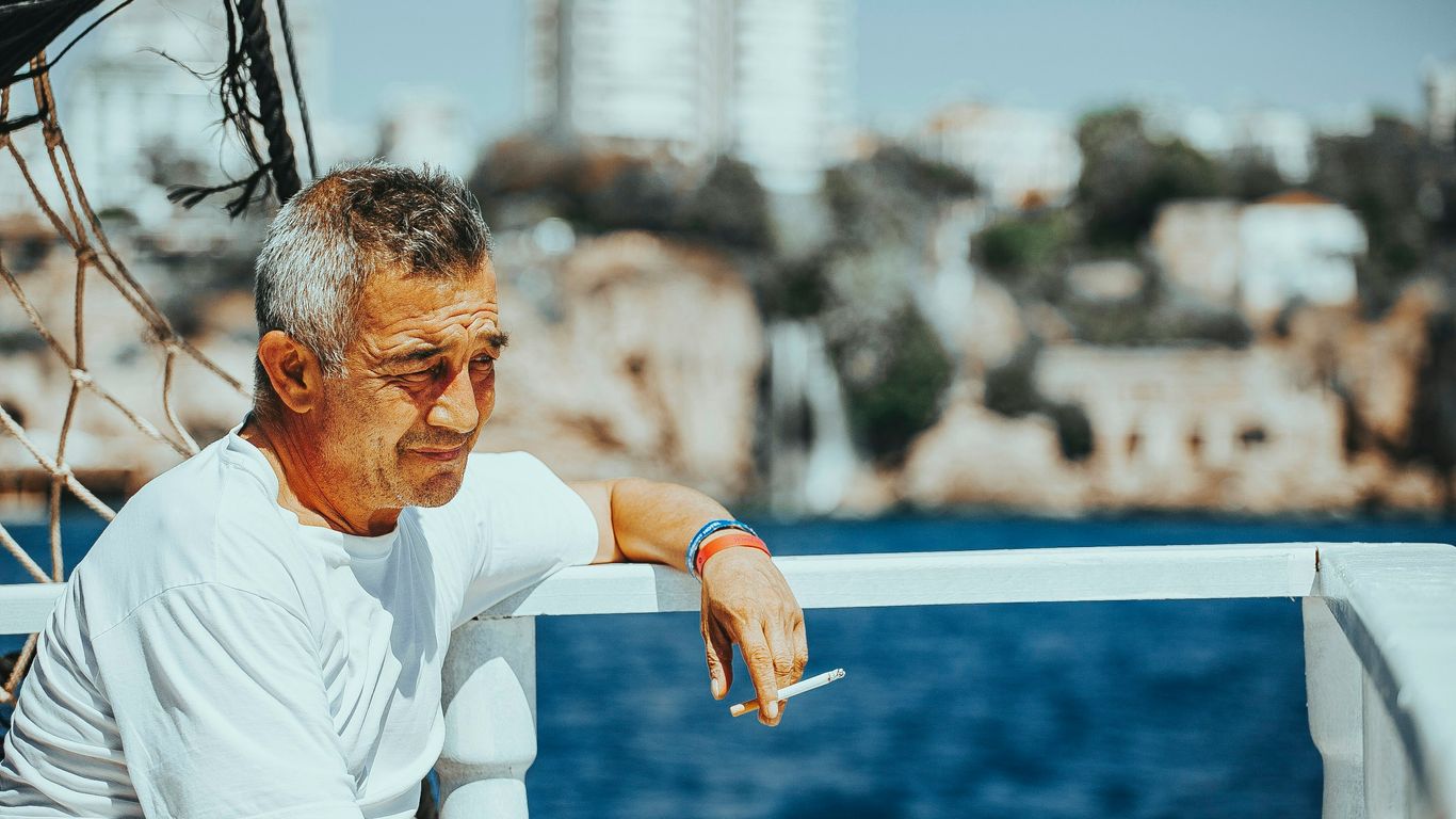 a man sitting on a boat holding a cigarette