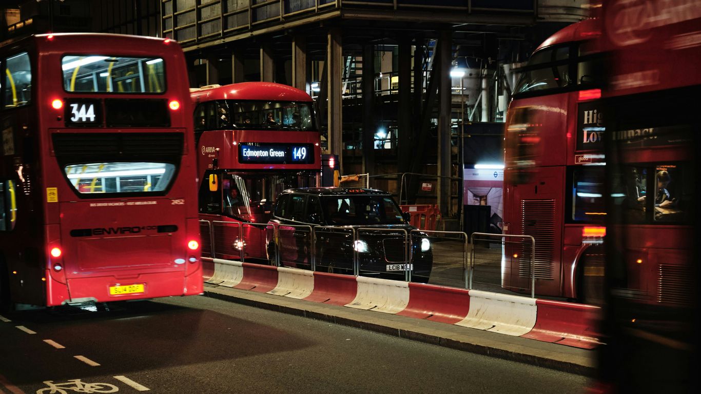 a couple of red double decker buses driving down a street