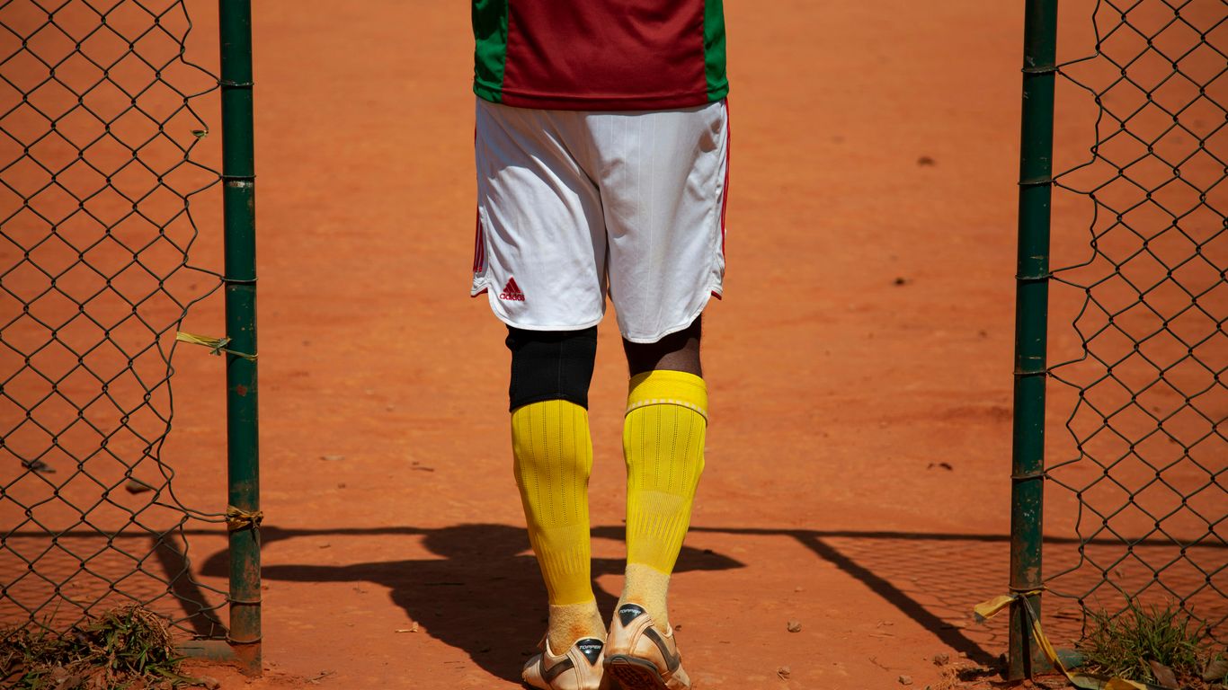 person in red shirt and yellow shorts standing on brown field