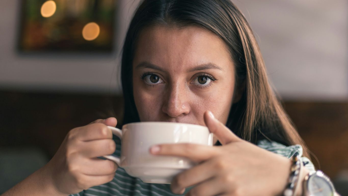 woman in black and white stripe long sleeve shirt holding white ceramic mug