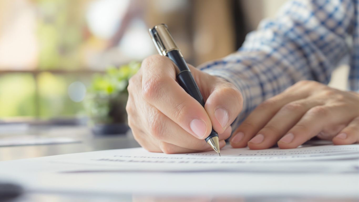 Hands holding a pen over a document.