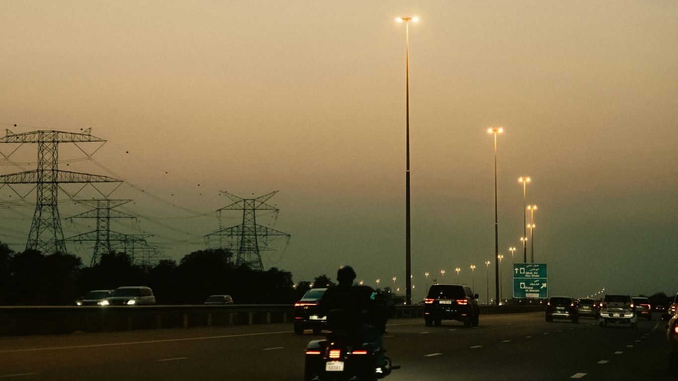 Motorcycle on highway at dusk with power lines.