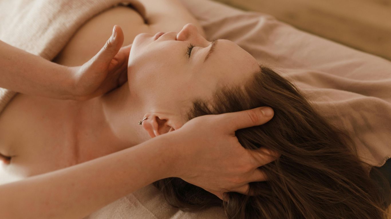 Person receiving a relaxing head and neck massage on table.