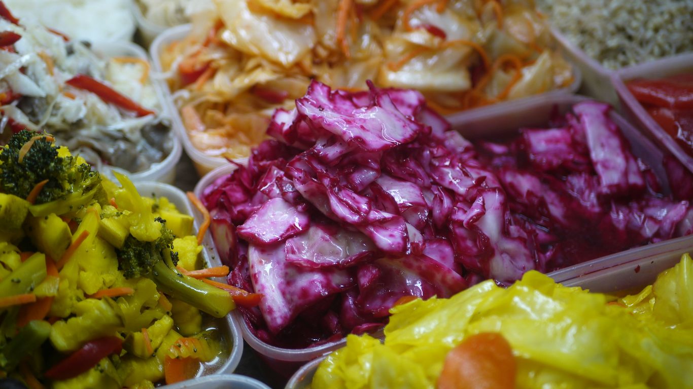 Assortment of colorful pickled vegetables in containers.