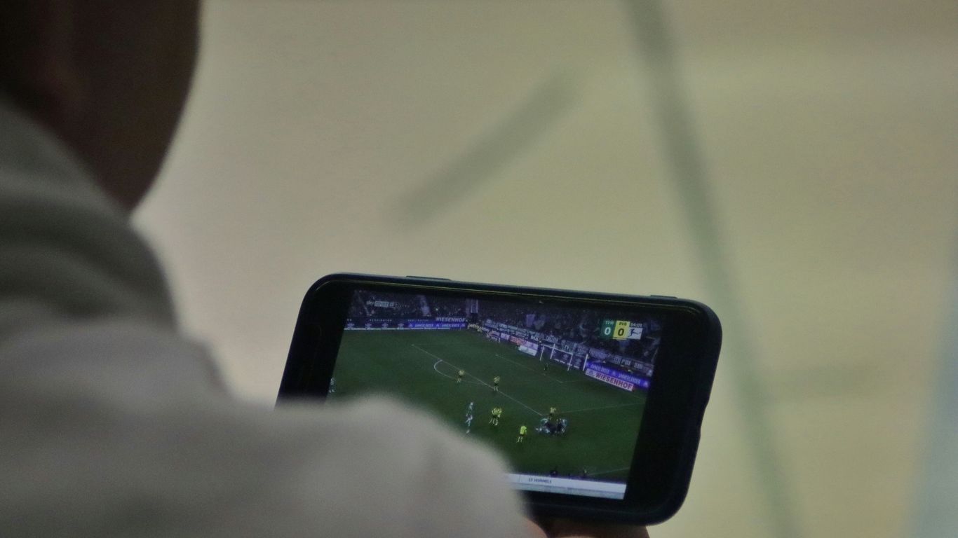 a man is playing a soccer game on his phone