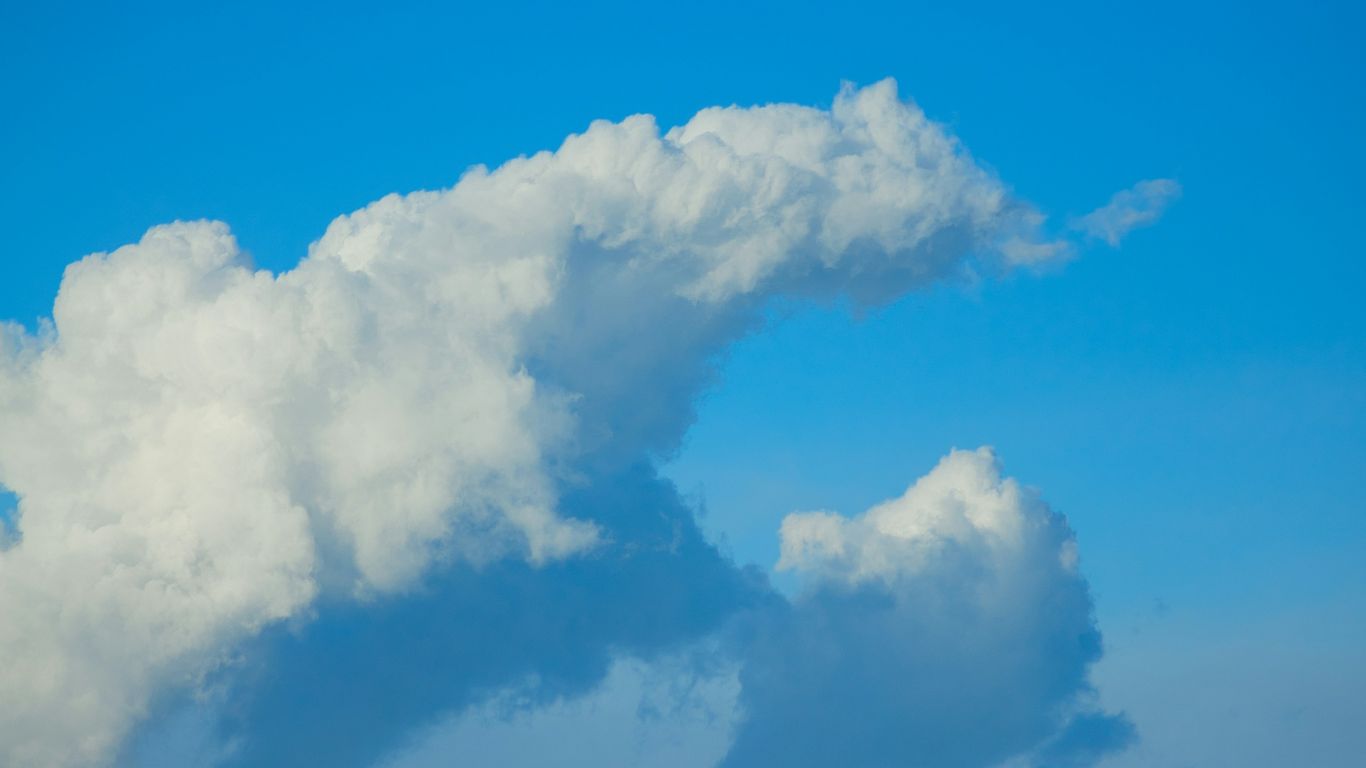 Fluffy cloud floats in bright blue sky.