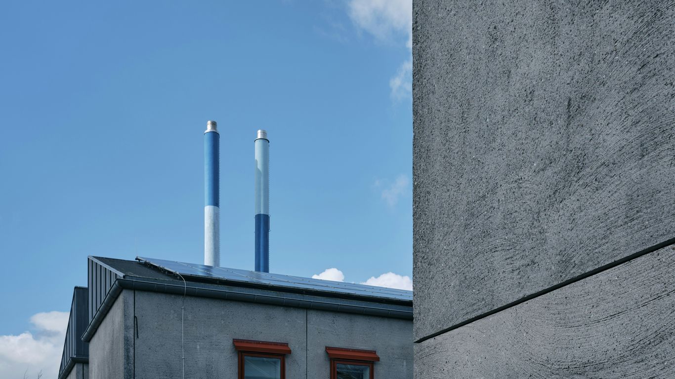 A grey building with a red door and two smoke stacks
