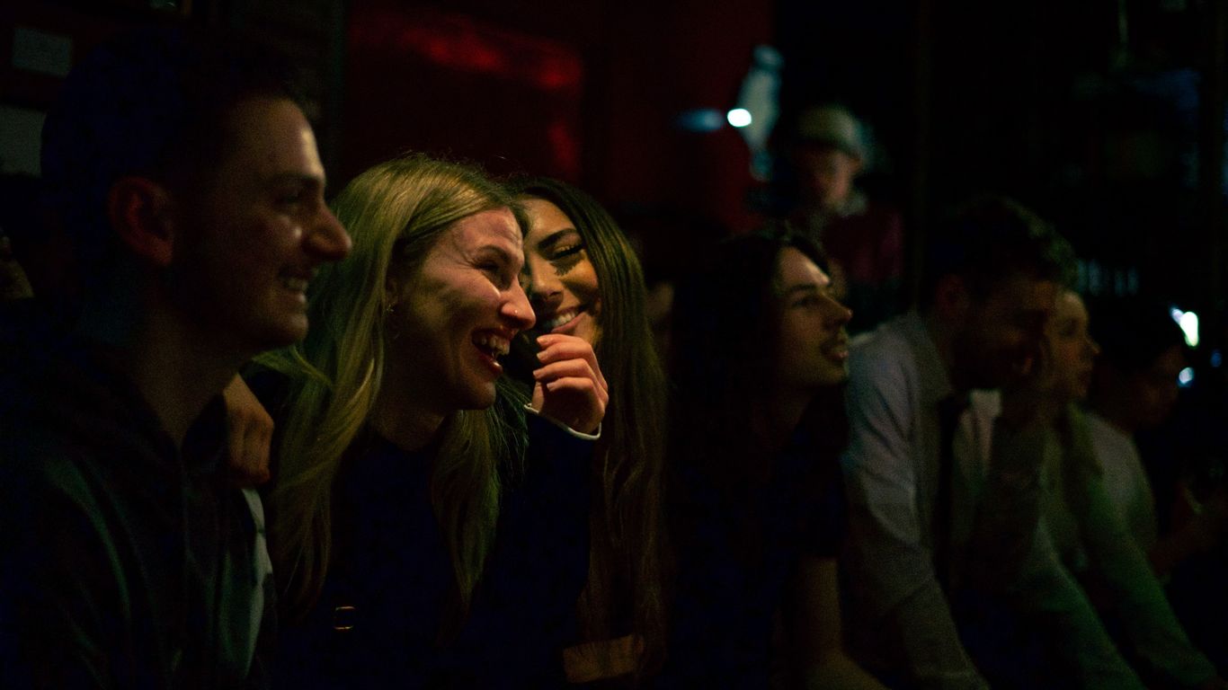A group of people laughing and enjoying themselves in a dimly lit setting.