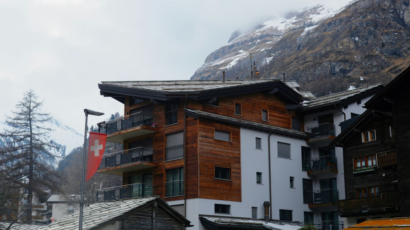 Wooden building with swiss flag near snowy mountains