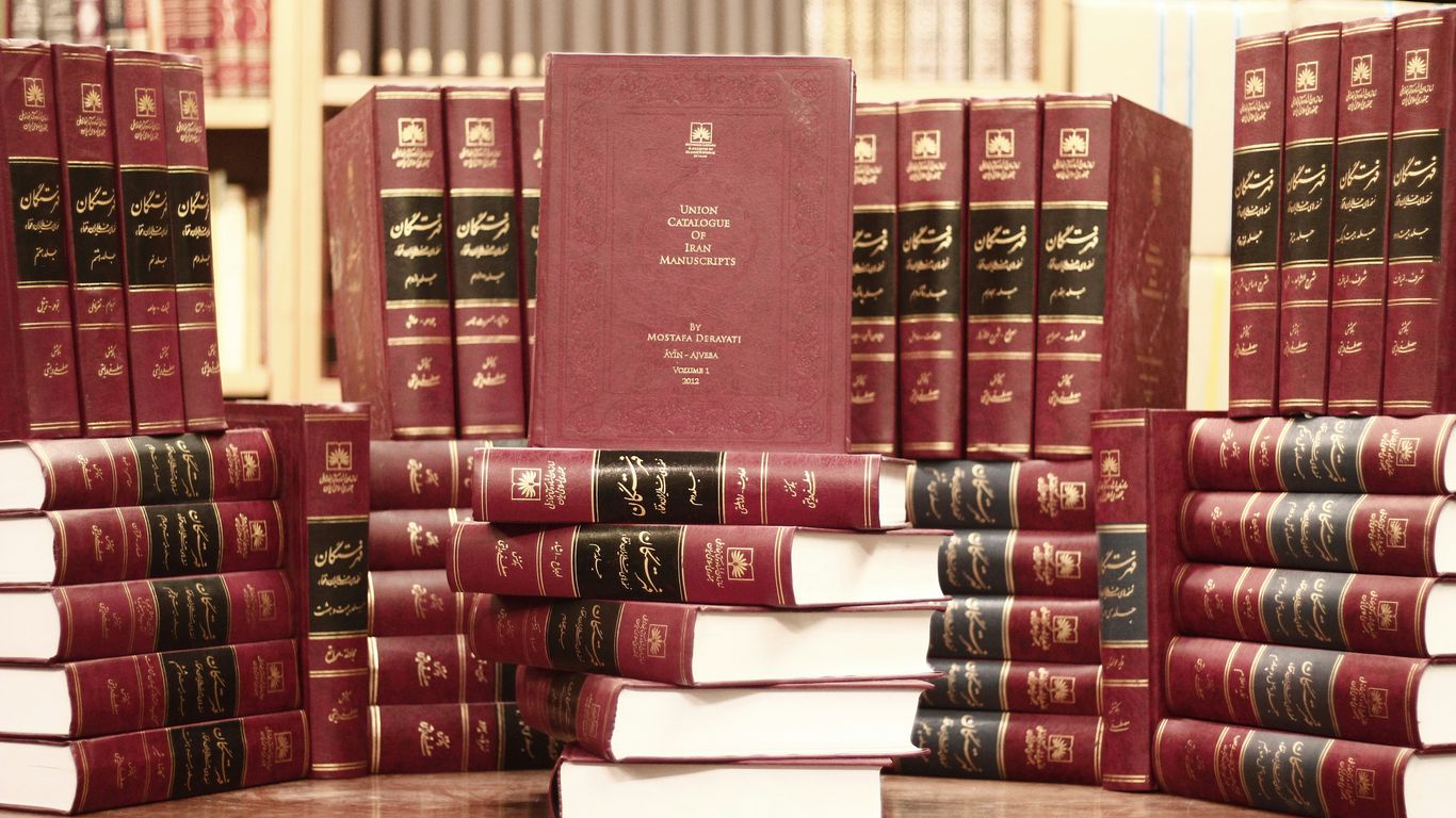 a stack of red books sitting on top of a wooden table
