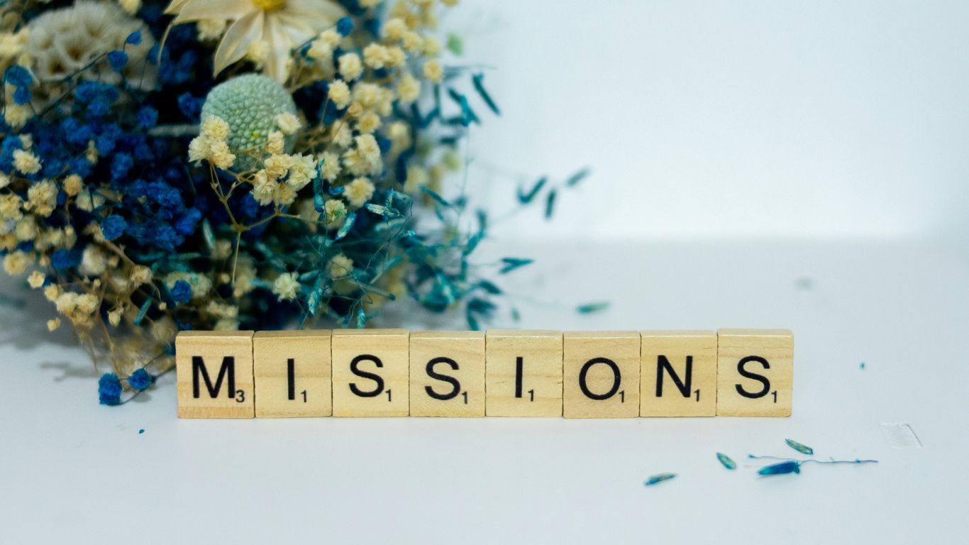 a scrabble type block spelling the word miss, sits next to a bouquet