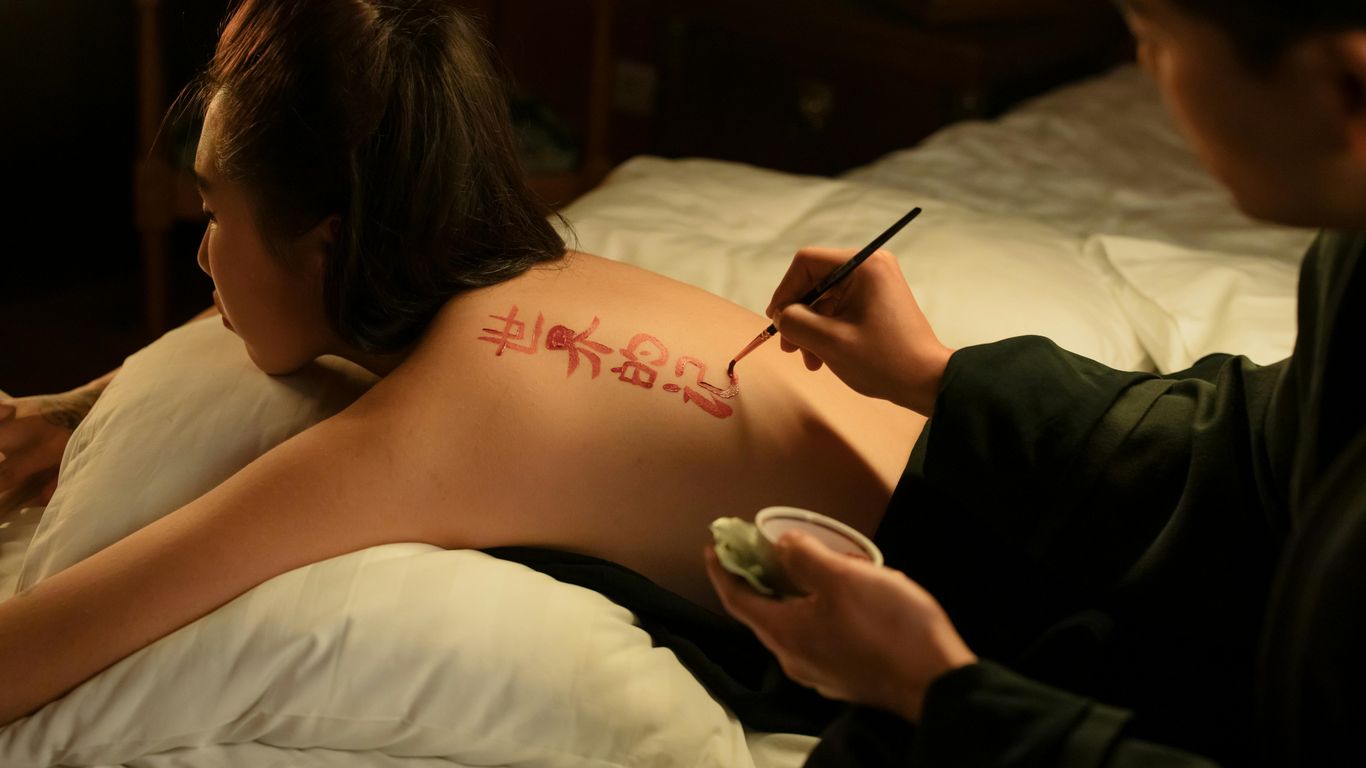 A person is painting red calligraphy on another person's back.