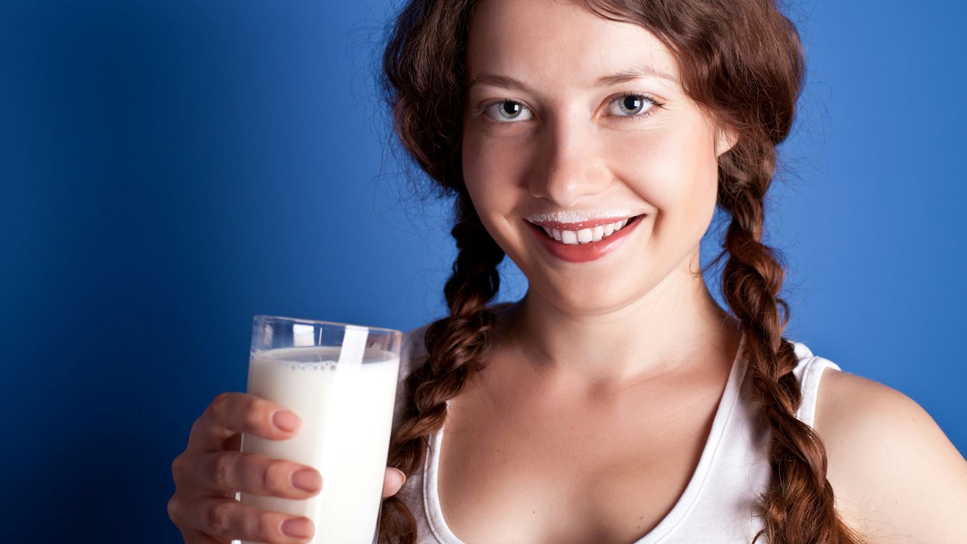A woman is holding a glass of milk