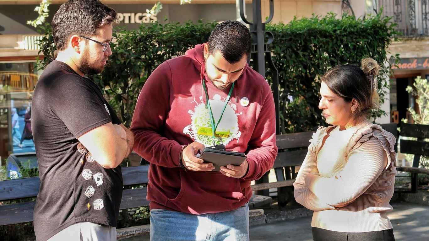Three people looking at a tablet outdoors device outdoors