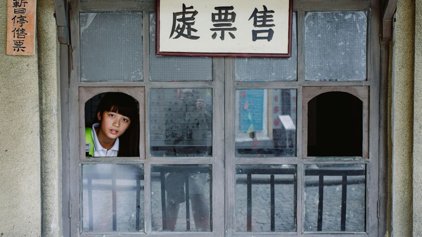 A person looks out of a window with Chinese signs.