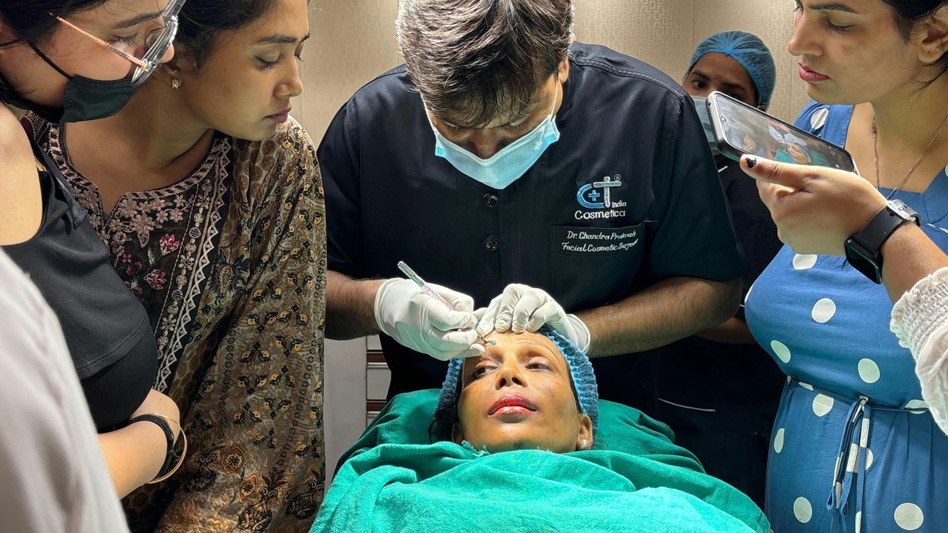A group of people standing around a woman in a hospital bed