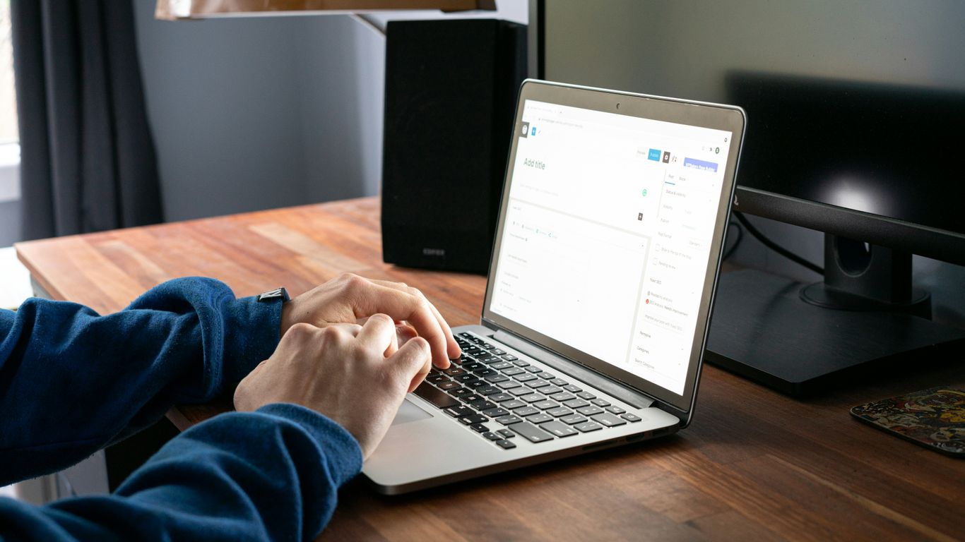 person using macbook pro on brown wooden table