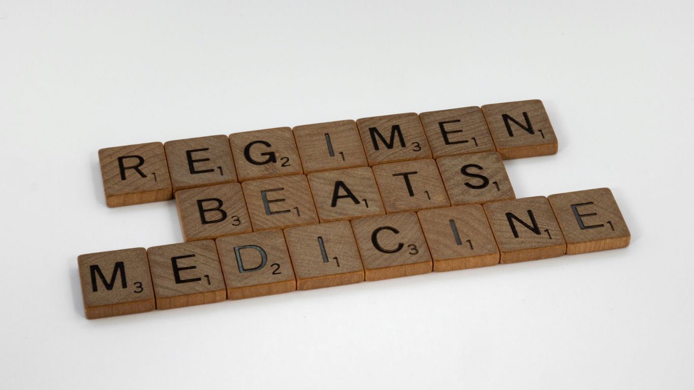 scrabble tiles spelling the word regimen beats medicine