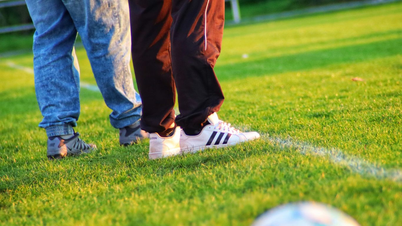 a pair of people's legs and shoes on a grass field