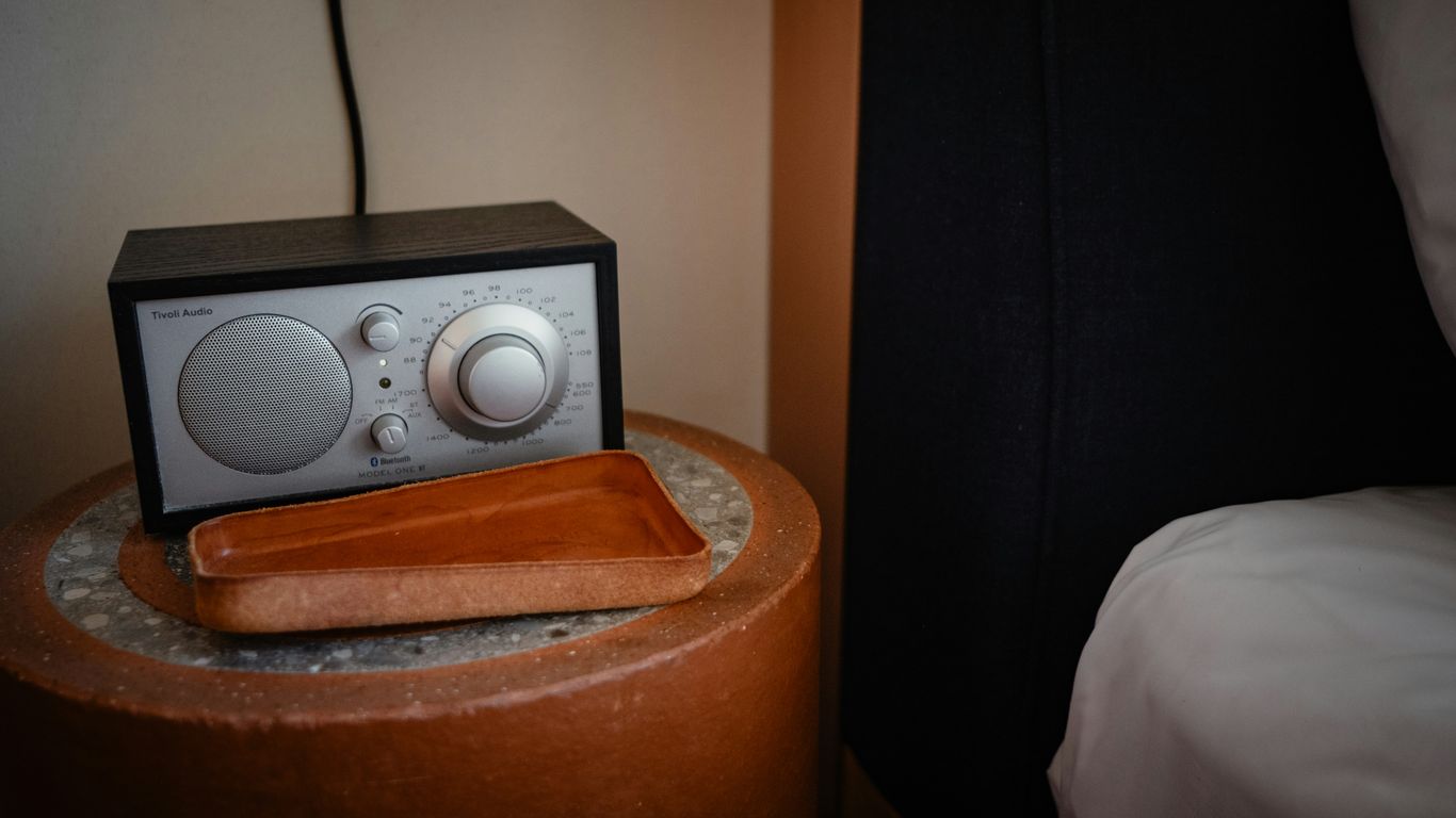 A radio, tray, and nightstand beside the bed.
