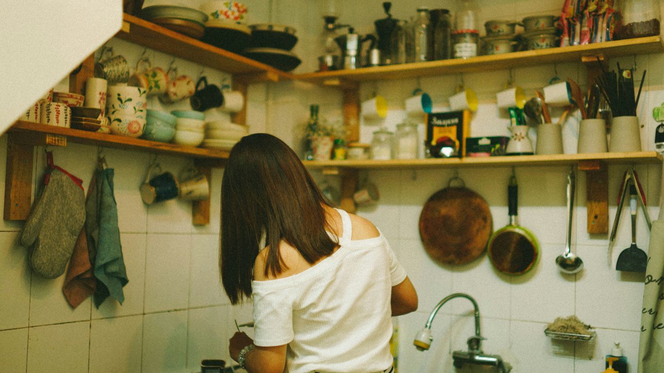 woman in white top standing beside table