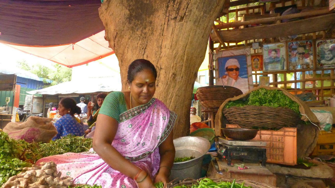 a woman sitting in front of a pile of vegetables