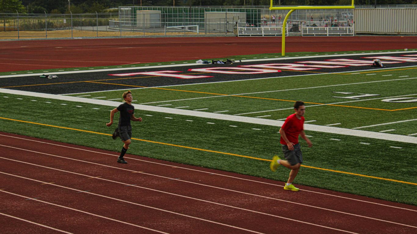 Two men running on a track in a stadium