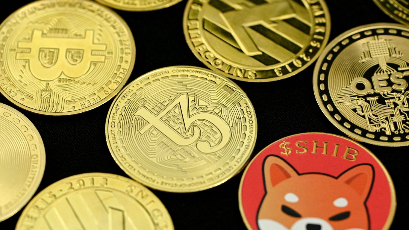 Various gold-colored cryptocurrency coins displayed on a black surface.