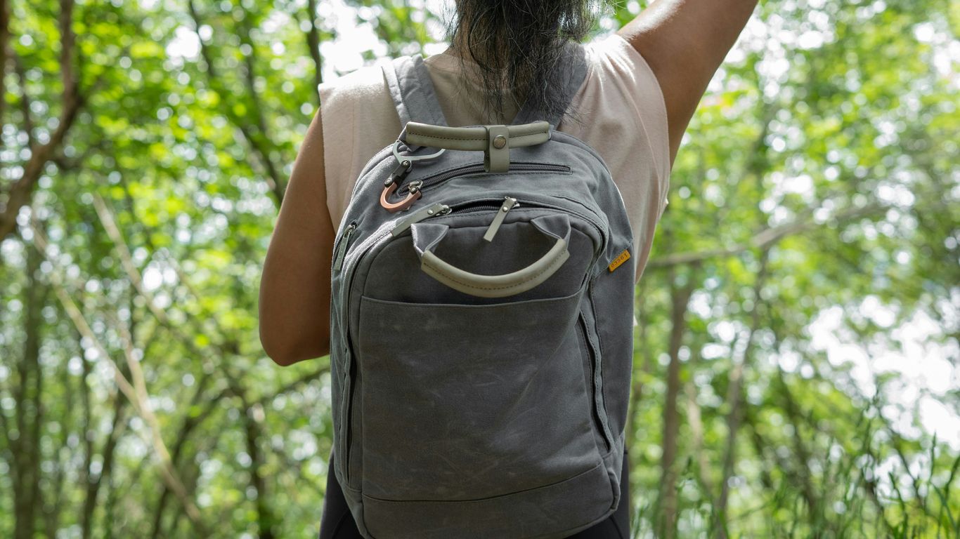 woman in gray t-shirt and black pants with brown backpack