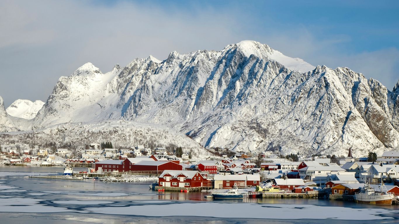 Snowy village nestled at the base of majestic mountains.