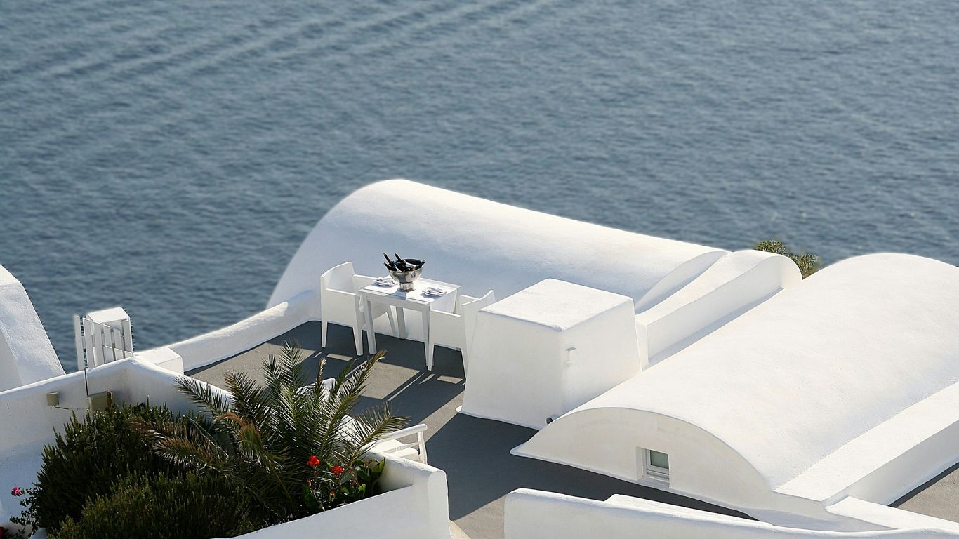 An aerial view of a white building with a body of water in the background