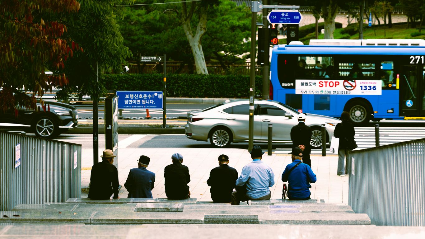 People sitting on stairs with city street in background