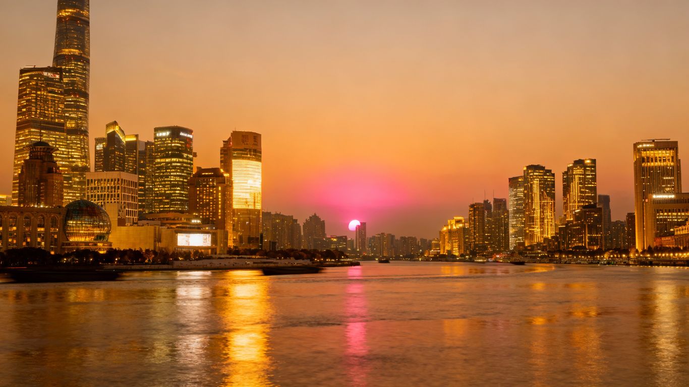 Shanghai skyline at dusk with a rising sun.