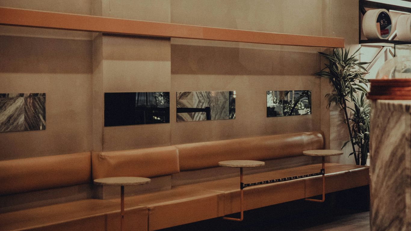 a long bench in a large room with a plant in the corner