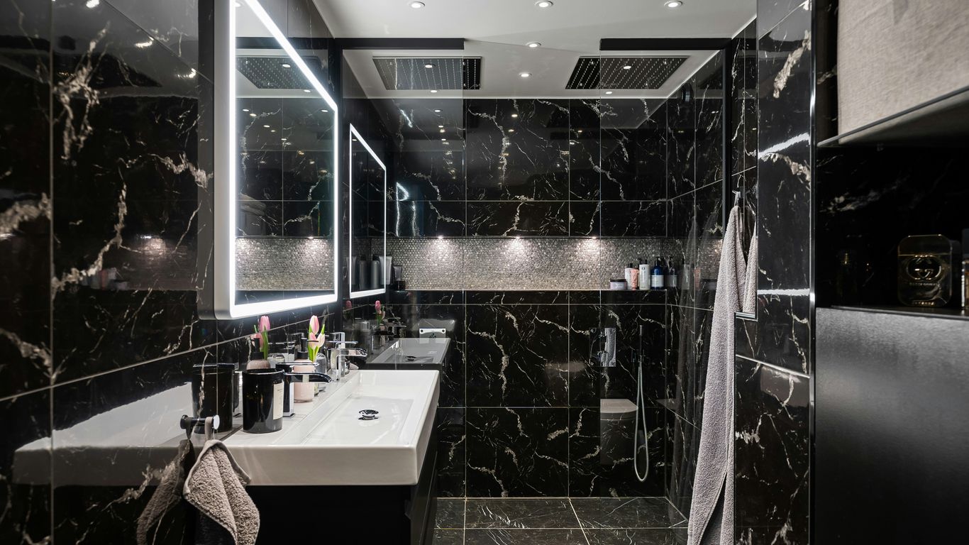 A black and white bathroom with a sink and mirror
