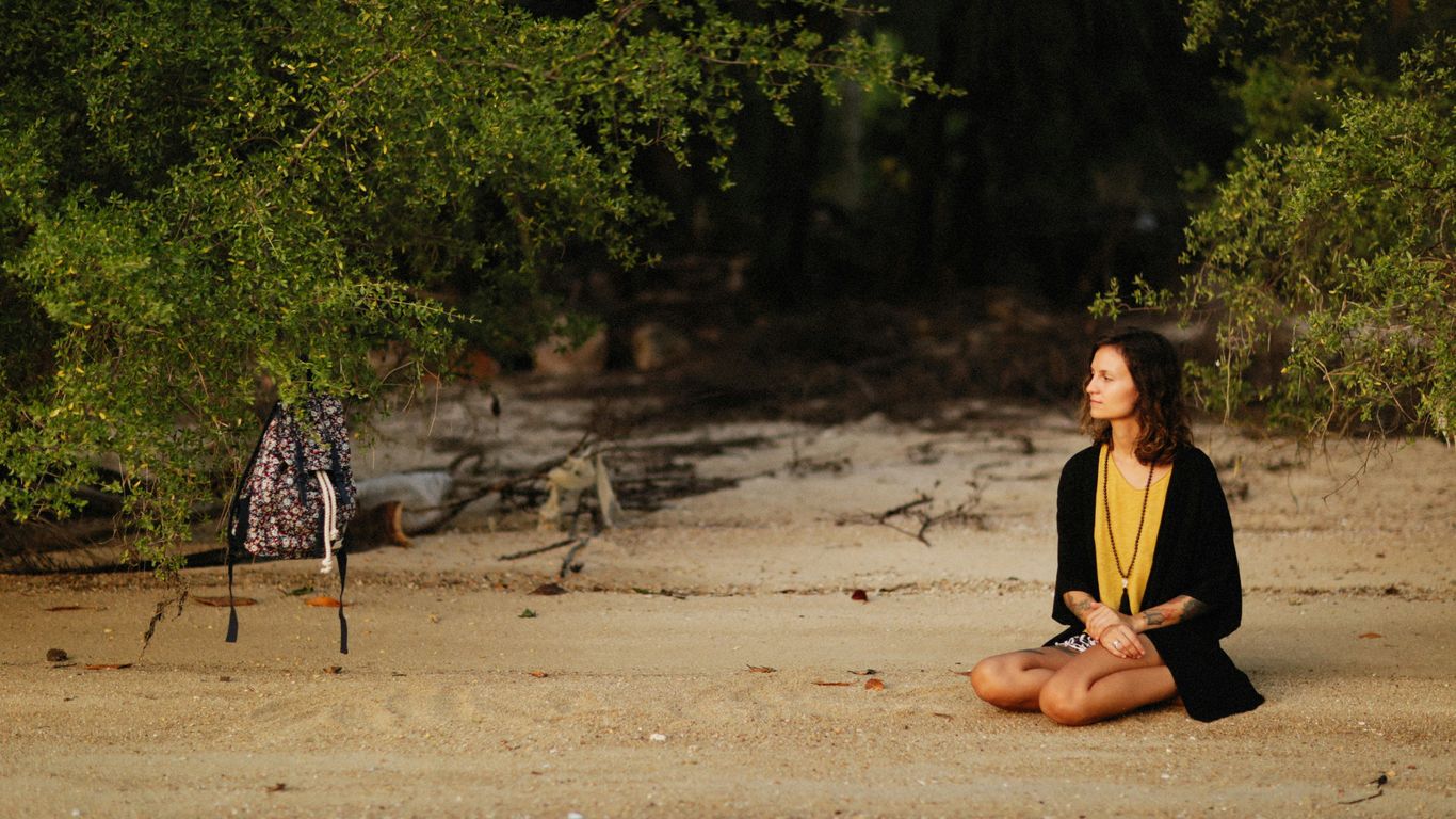 a woman sitting on the ground in front of a body of water
